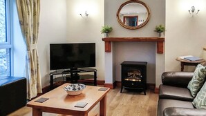 Una sala de estar con televisión, chimenea, sofá y una mesa con un tazón.