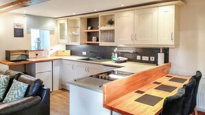 Cocina funcional con armarios blancos, horno integrado y comedor con mesa y sillas de madera.