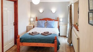 Un dormitorio con una cama de madera, dos mesitas de noche, una araña y un radiador.
