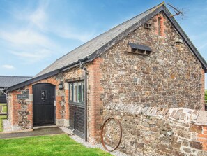 A stone building with a black door and windows, a small porch, and a metal antenna on the roof. - Trespaddick - UK40041 (Crackington Haven)
