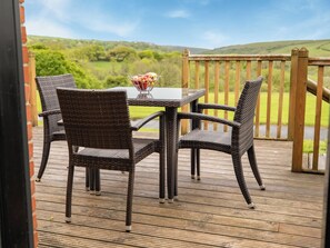 A wooden deck with wicker chairs and a table, overlooking a green landscape. - Trespaddick - UK40041 (Crackington Haven)