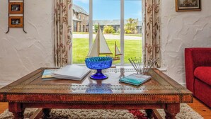 A room with a large window, a sailboat model, a blue glass bowl, and a red chair. - 1 bedroom accommodation in Crackington Haven (Crackington Haven)