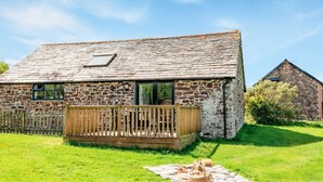 A stone cottage with a wooden deck and a grassy yard. - 1 bedroom accommodation in Crackington Haven (Crackington Haven)
