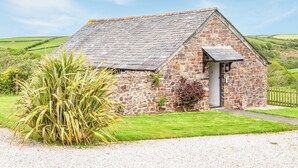 A stone cottage with a sloped roof, a small porch, and a gravel driveway. - 1 bedroom accommodation in Crackington Haven (Crackington Haven)
