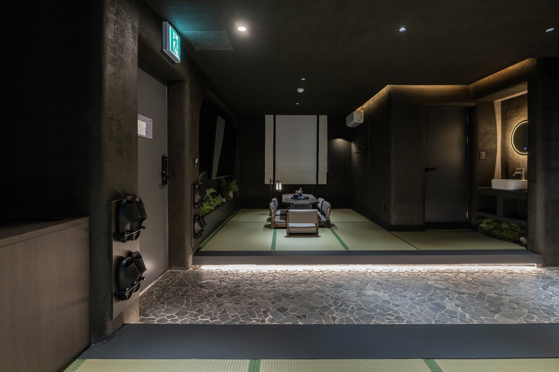 A room with tatami mats, a tatami mat table, a mirror, a sink, and a small plant.