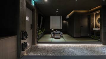 A room with tatami mats, a tatami mat table, a mirror, a sink, and a small plant.