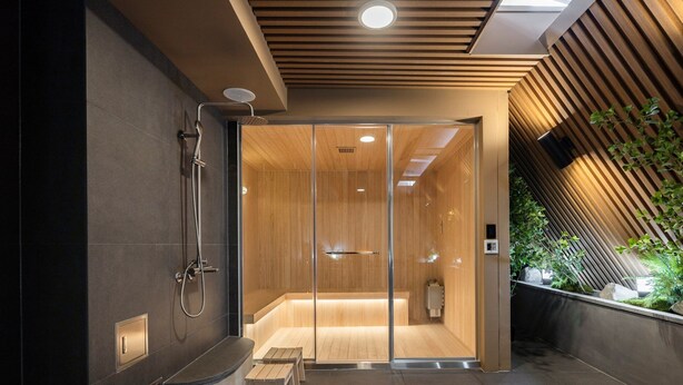 Een moderne douche met een glazen deur, een zitbankje en een handdoekhouder.