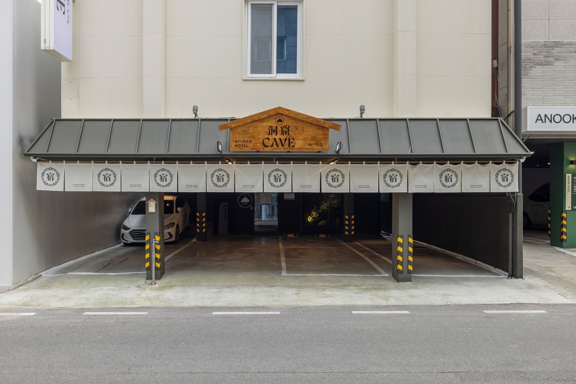 A hotel entrance with a sign reading 'Ryokan Cave Hotel' and multiple entrance doors.