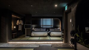 Een moderne hotelkamer met een groot bed, nachtkastjes, een klein bureau en uitzicht op de stad.