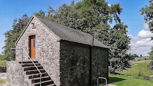 Ein Steinhaus mit einer Holztür und einer Treppe, die davor hinaufführt.