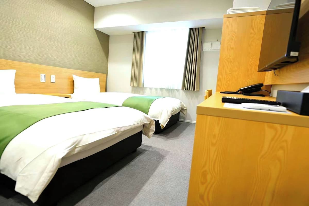 A hotel room with two beds, a desk, and a telephone.
