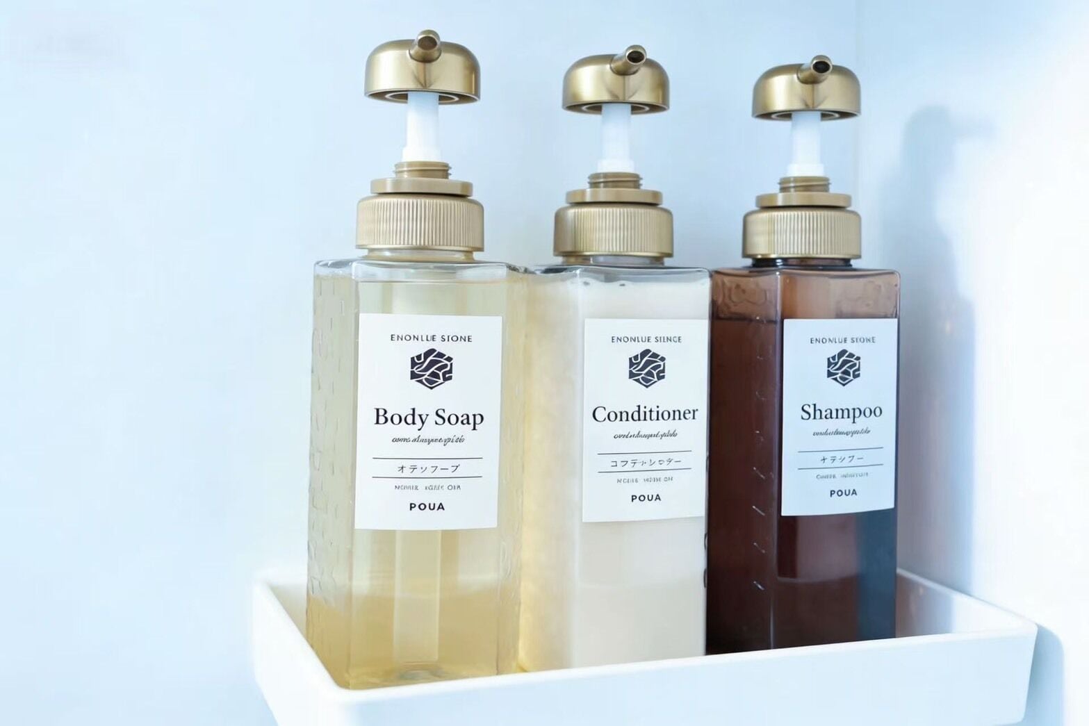 Three bottles of Enonlue Sione body care products: body soap, conditioner, and shampoo, each with a pump dispenser and labeled in both English and Japanese.