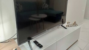 Un téléviseur à écran plat, posé sur un meuble blanc, avec une télécommande également posée sur le meuble.