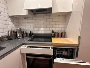 A modern kitchen with white cabinets, a black countertop, a built-in oven, and a dish rack. - Five Ways Coffee Lover Home away from Home (Birmingham)