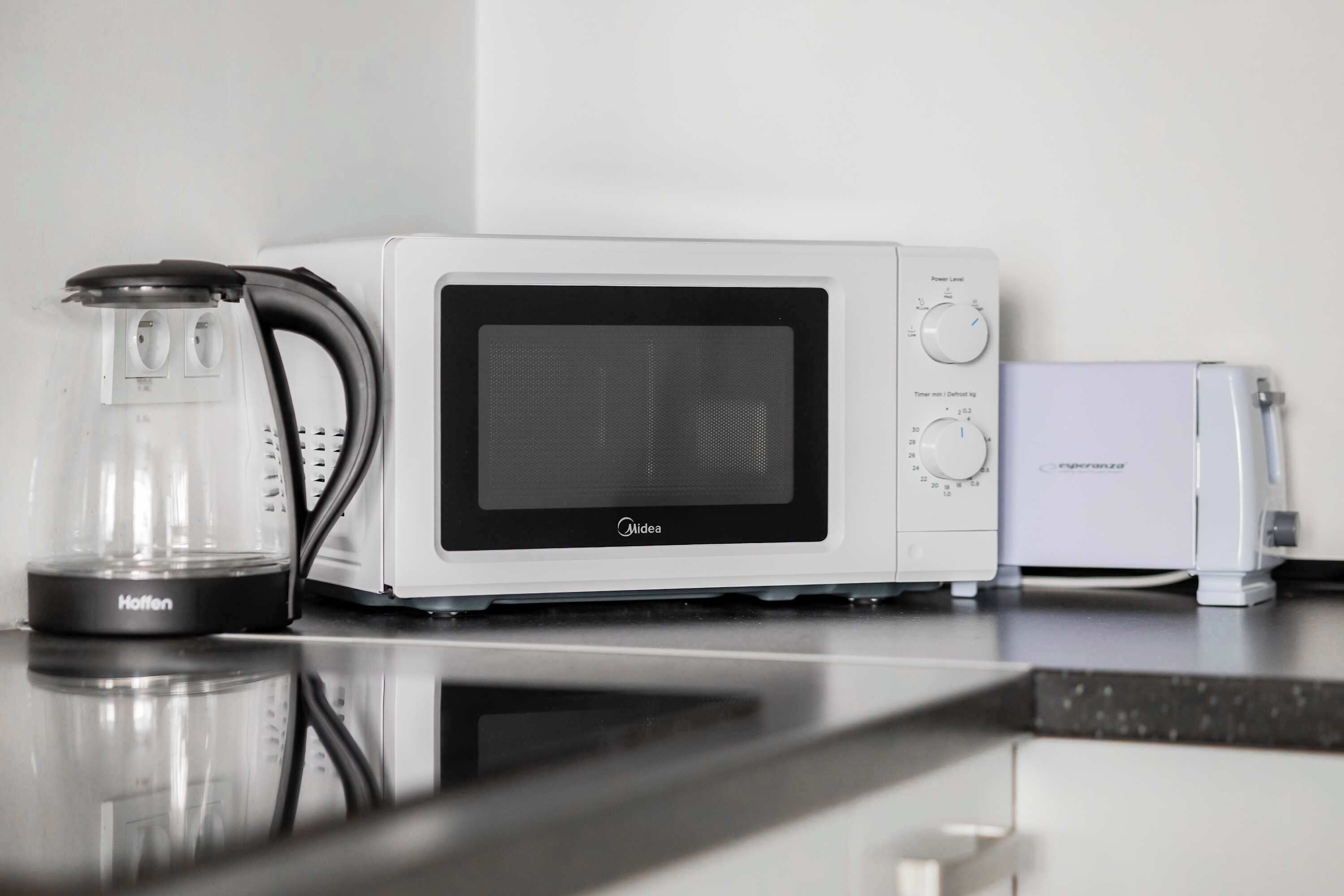 Eine Küche mit einer weißen Mikrowelle, einer Glaskaffeemaschine und einem Toaster.