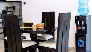 A dining area with a black table and chairs, a water dispenser, and a water bottle on the wall. - Cozy 2-bedroom apartment in perfect Nairobi with fitness room WESTLANDS (Nairobi)