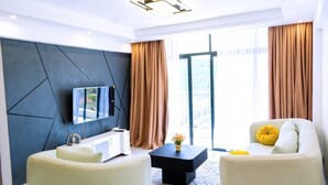 A modern living room with a sofa, a coffee table, and a TV mounted on a wall with geometric patterns. - Cozy 2-bedroom apartment in perfect Nairobi with fitness room WESTLANDS (Nairobi)