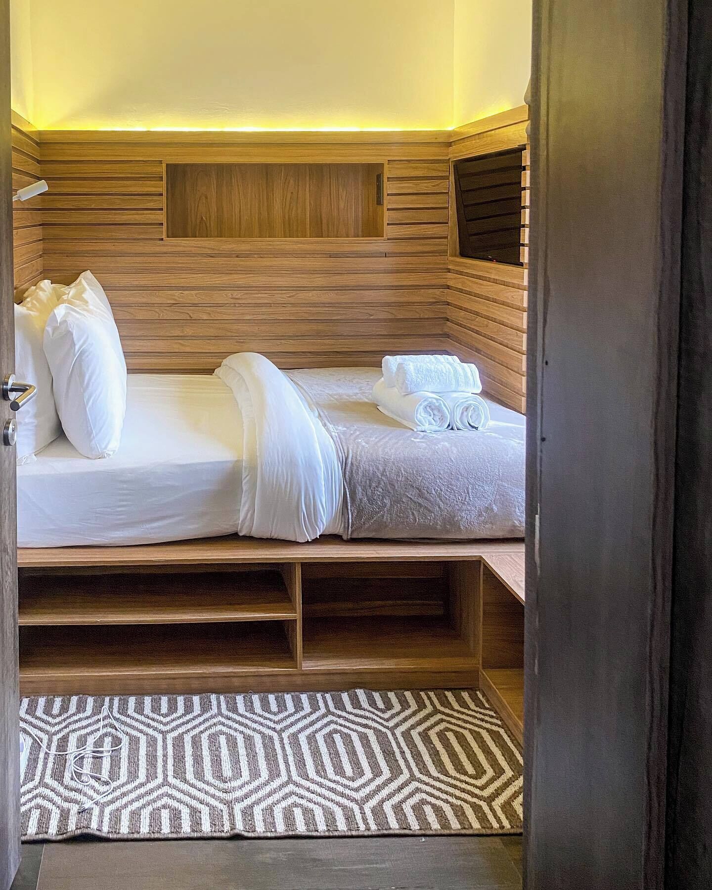 Un lit simple avec une literie blanche, une tête de lit et un panneau en bois décorant la tête de lit.