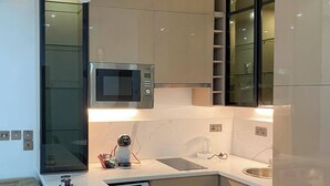 A modern kitchen with a built-in microwave, a coffee machine, and a dishwasher. - Dyve Luxury Stays (Abuja)