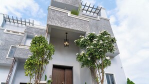 A modern building with a prominent wooden door, a balcony with a railing, and a small window. - Dyve Luxury Stays (Abuja)