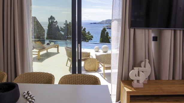 A room with a view of a pool and the sea, furnished with wicker chairs and a wooden table. - Villa Marenthe | 3 BDR | Sea Views | Pool | Syros (Syros)