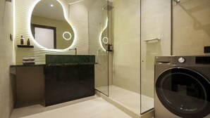 A modern bathroom with a glass shower enclosure, a built-in washing machine, and a vanity with a mirror. - Villa Marenthe | 3 BDR | Sea Views | Pool | Syros (Syros)