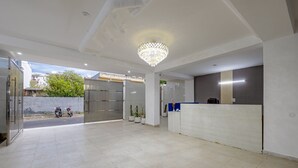 A spacious lobby with a reception desk, a chandelier, and potted plants. - Yashobhoomi Suites near Yashobhoomi Convention Centre (New Delhi)