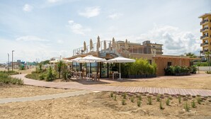 A beachside restaurant with outdoor seating, a wooden deck, and a view of the sea. - Friendly Mobile Home in Rimini Family Village (Rimini)
