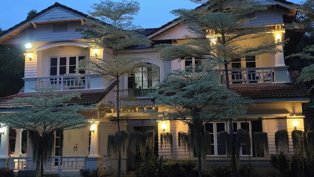 Una grande casa a due piani con numerosi balconi e una facciata ben illuminata.