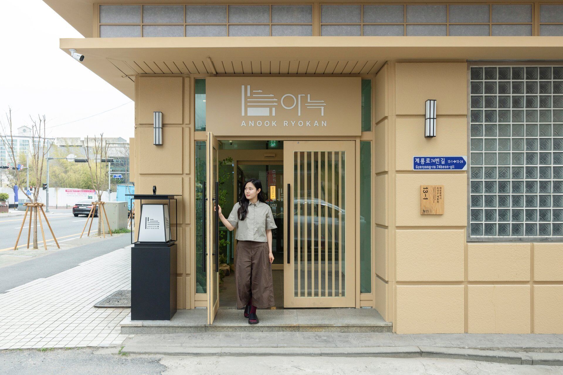 Entrada de un hotel con un letrero que dice 'ANOOK RYOKAN' y un letrero azul que indica la habitación número 74.