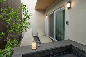 A small outdoor seating area with a table lamp, a chair, and a glass door. - Anook Ryokan Hotel Daejeon Yuseong (Daejeon)