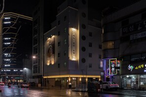 A hotel with multiple floors, a prominent sign with a logo, and a well-lit entrance. - Anook Ryokan Hotel Daejeon Yuseong (Daejeon)