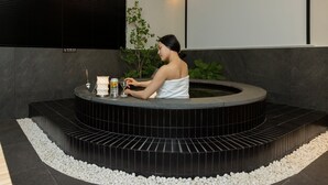 Zona de spa con un jacuzzi, una planta y una botella de bebida.
