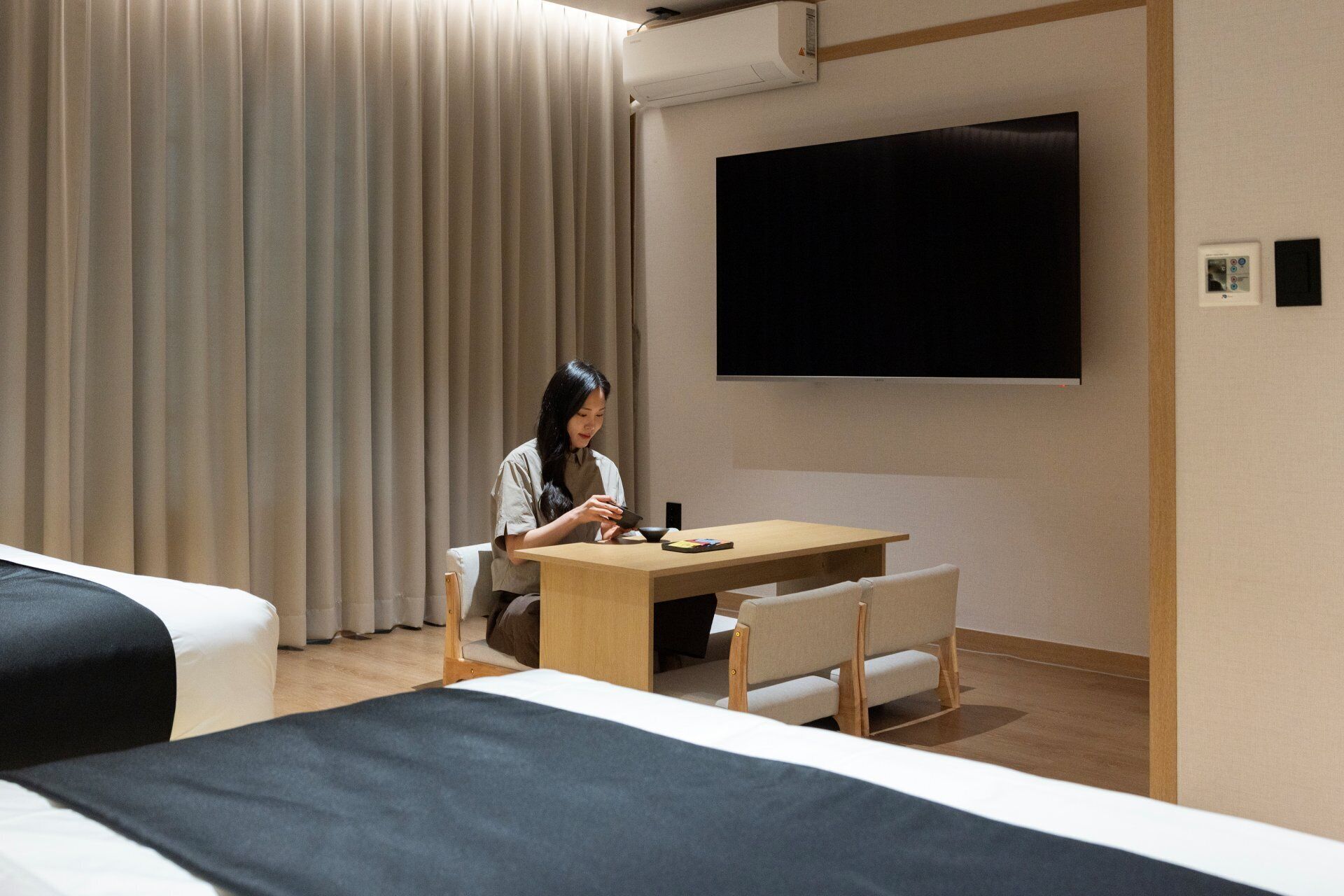A hotel room with a bed, a desk, a chair, a television, and a curtain.