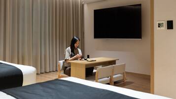 A hotel room with a bed, a desk, a chair, a television, and a curtain.