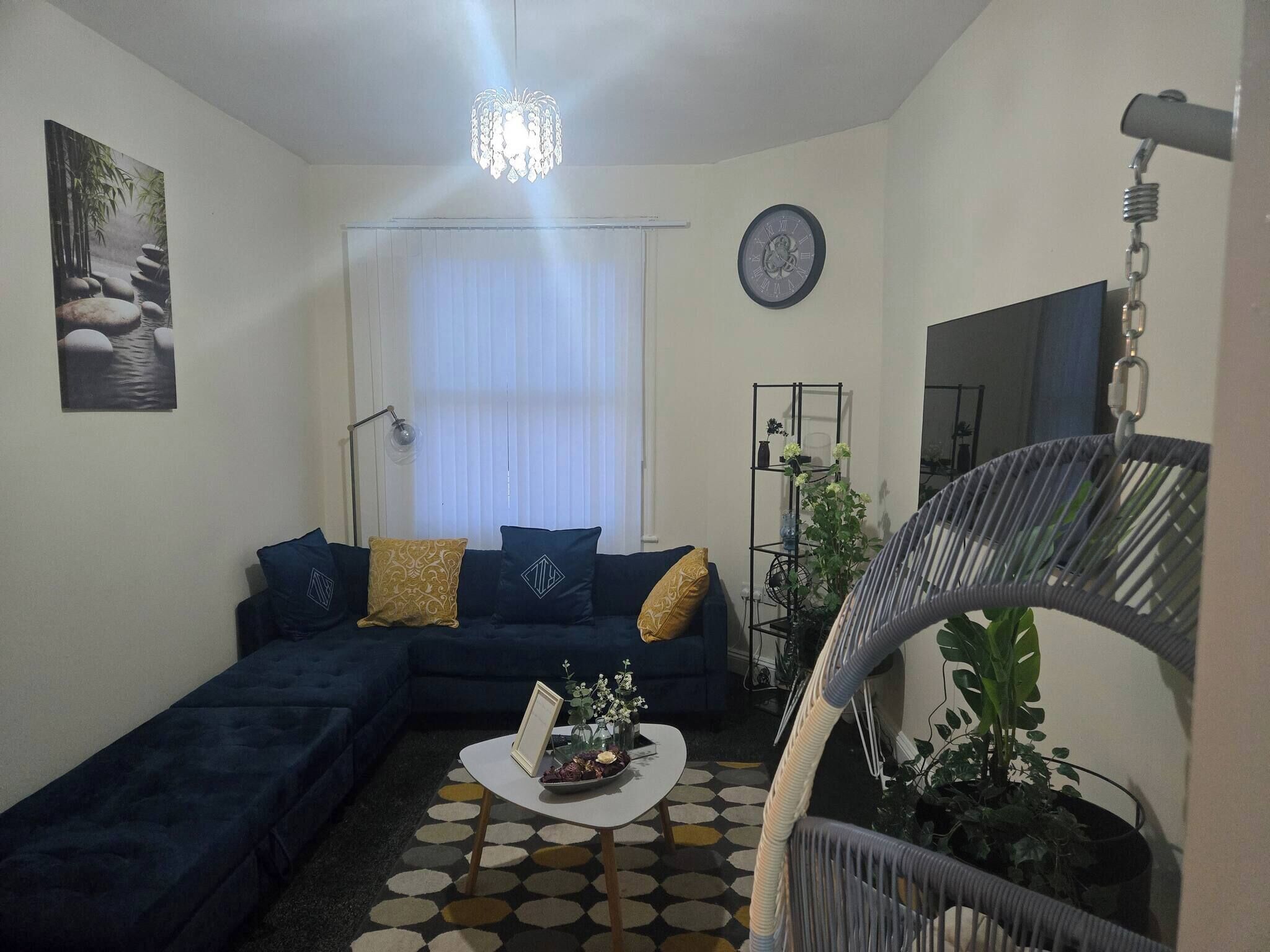 A living room with a dark blue sofa, a round coffee table, and a staircase with a chair.