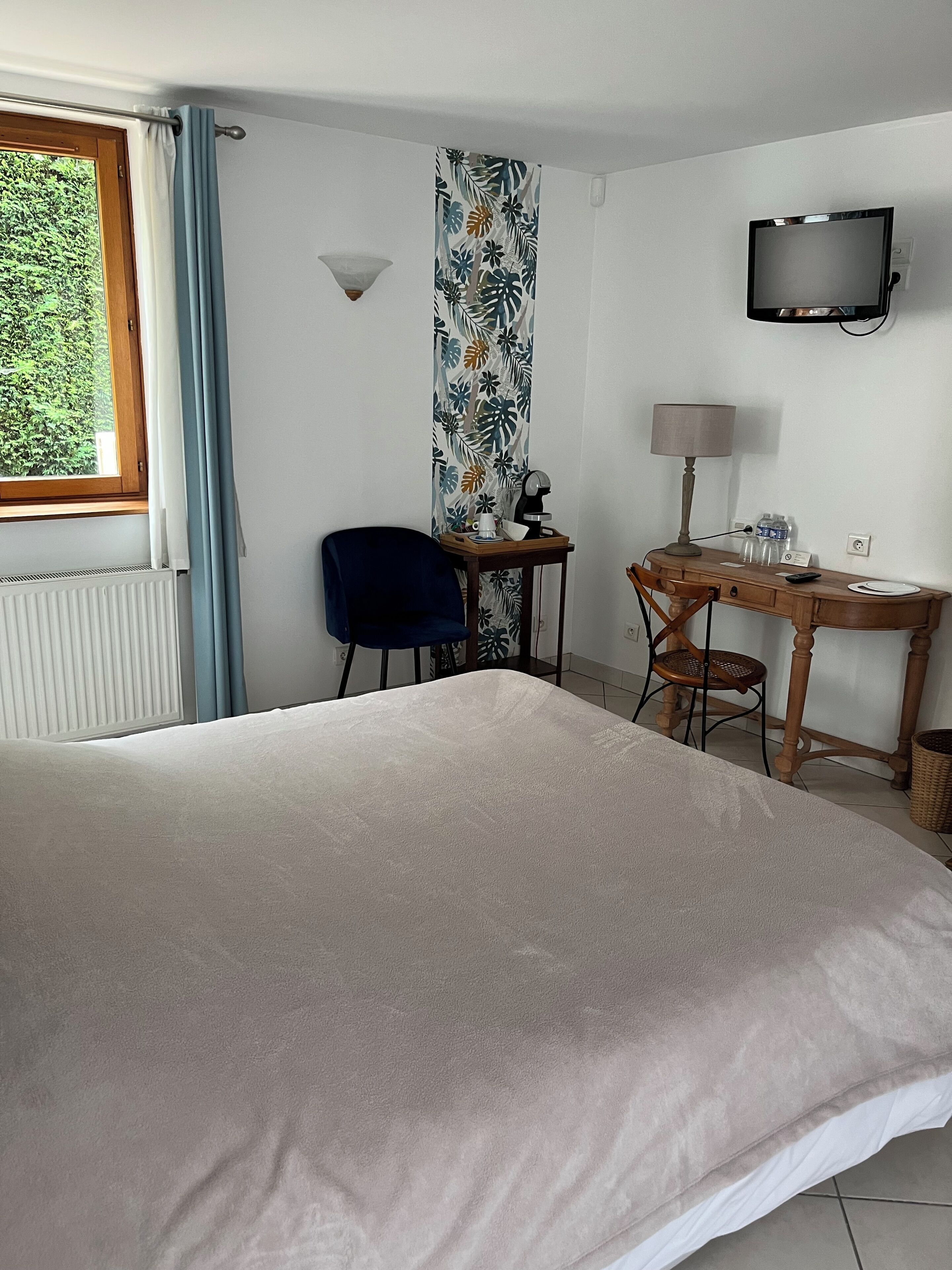 A hotel room with a bed, a desk, a chair, a television, and a window with curtains.
