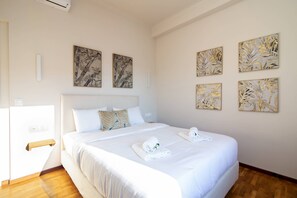 A hotel room with a large bed, a bedside table, and a wall-mounted air conditioning unit. - Pinia Penthouse by Corfuescapes (Corfu)