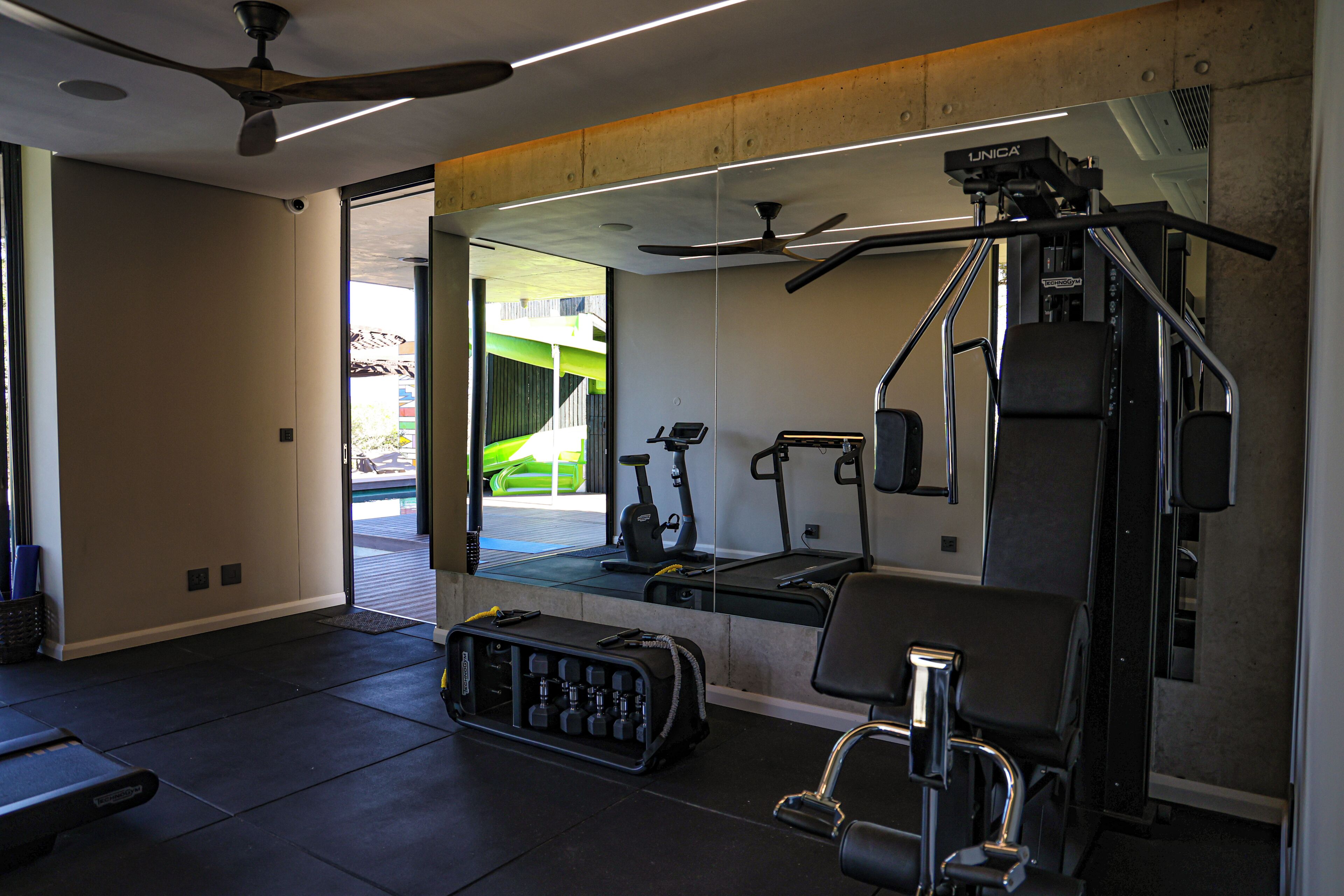 Une salle de sport moderne équipée de matériel d’exercice, de supports pour les poids et d’un miroir.