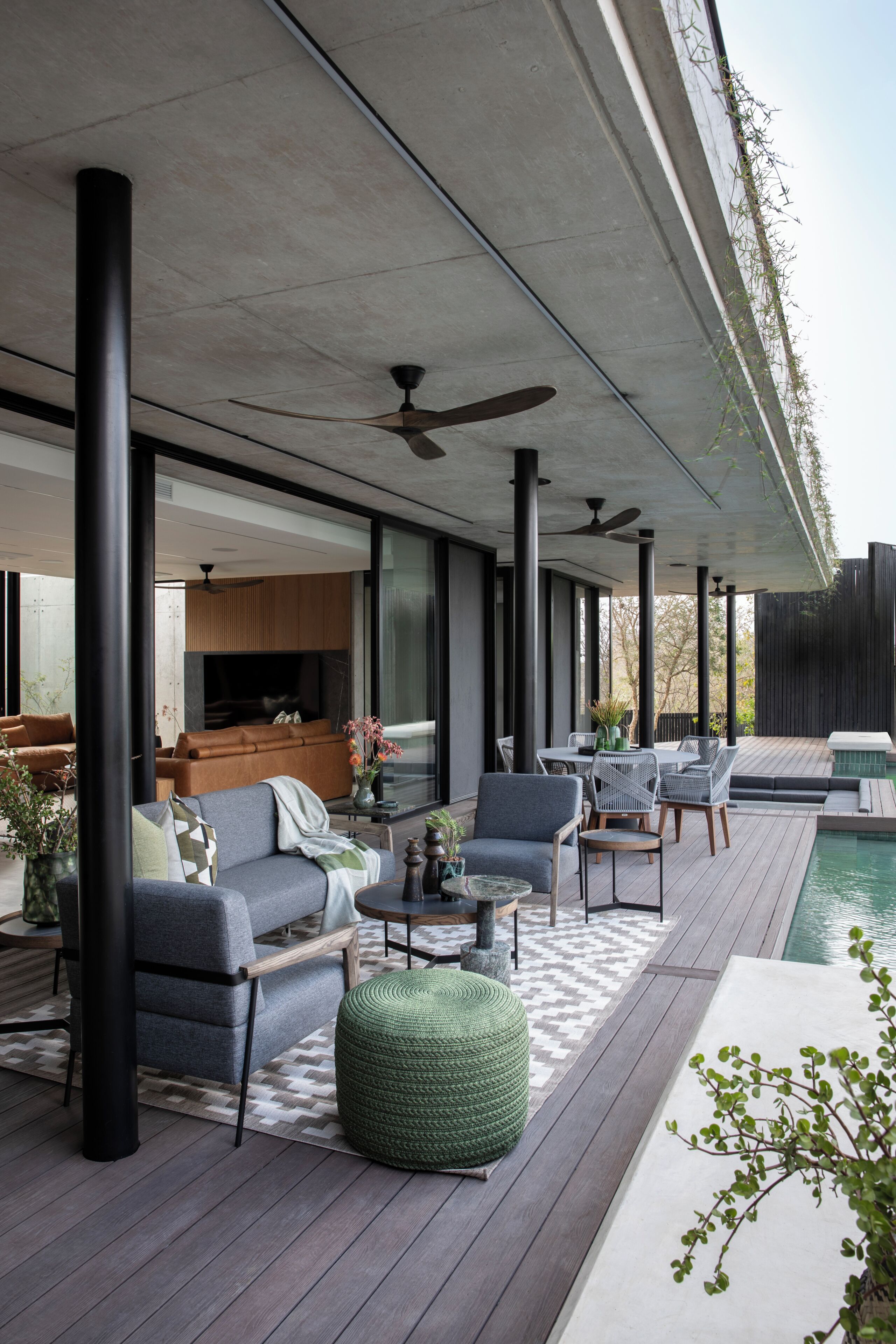 Un espace de vie extérieur moderne, doté d’une piscine, d’un coin salon et offrant une vue sur le paysage environnant.