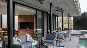 Un espace de vie extérieur moderne, doté d’une piscine, d’un coin salon et offrant une vue sur le paysage environnant.