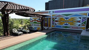 Un área de piscina con sillones reclinables y una pérgola.