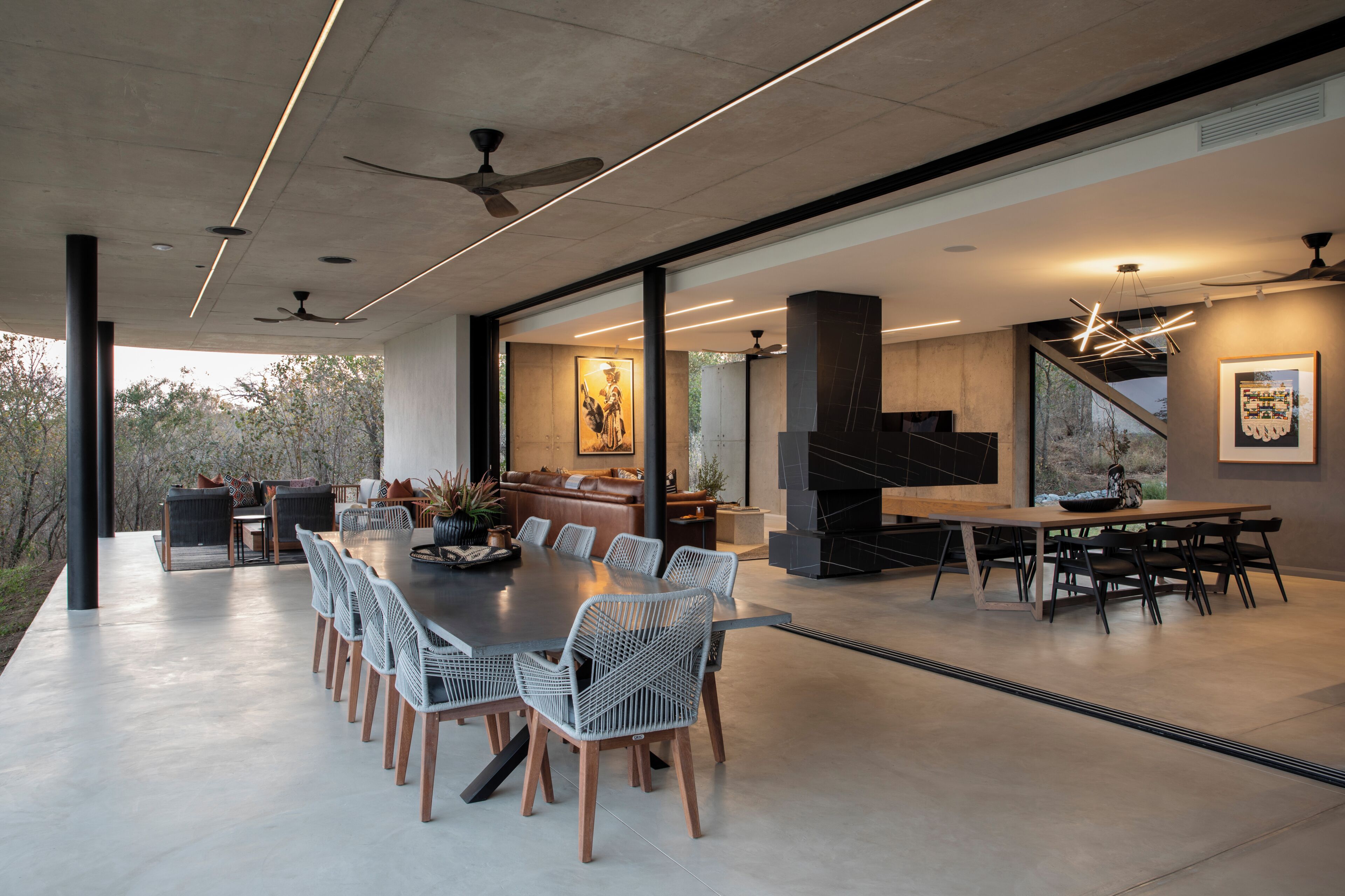 Un espace repas moderne avec une longue table, des chaises et une cheminée.