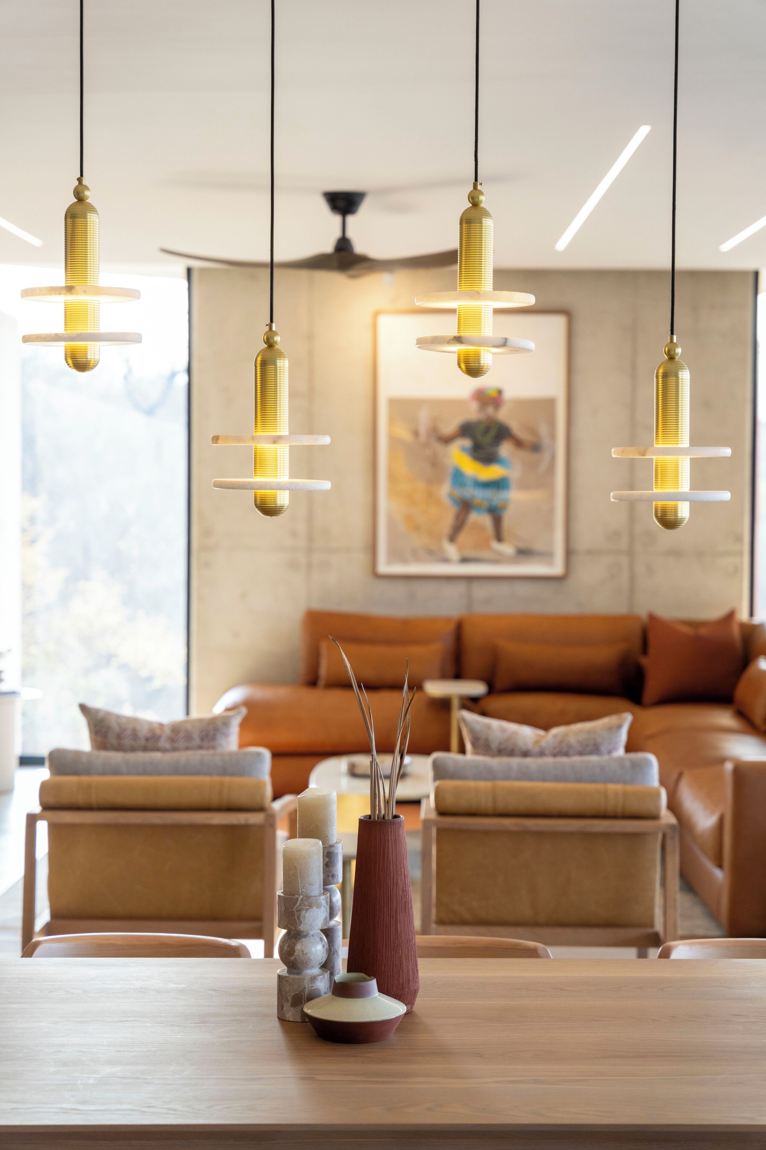 Un salon moderne comprenant un canapé, deux fauteuils, une table basse et des luminaires suspendus.