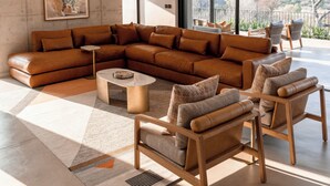 Una sala de estar moderna con un sofá modular, una mesa de centro y dos sillones.
