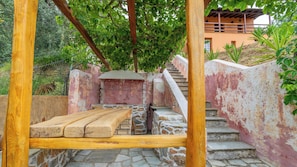 Una escalera de piedra que sube a una terraza de madera con un banco.