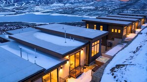 Un complesso moderno di edifici collegati, con ampie finestre e un paesaggio innevato con montagne sullo sfondo.