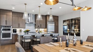 Una cucina moderna con elettrodomestici in acciaio inossidabile, un'isola centrale e illuminazione a sospensione.