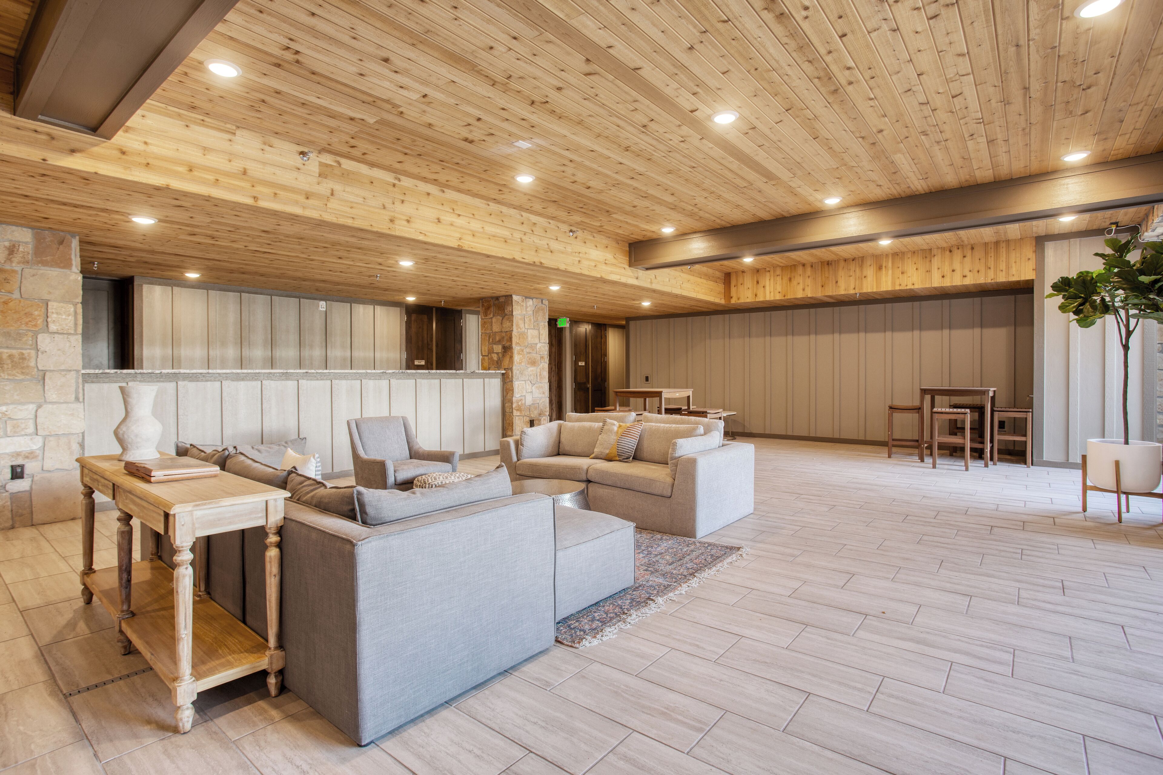 A spacious lobby with a wooden ceiling, a stone accent wall, and a seating area with sofas and a coffee table.