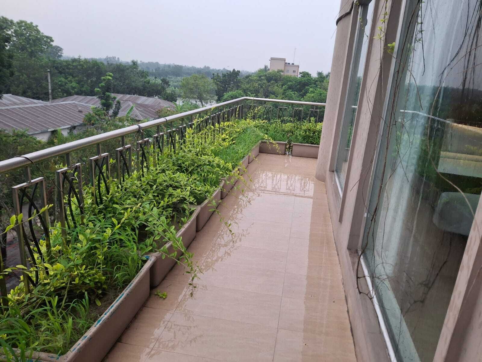 A balcony with a metal railing, potted plants, and a tiled floor.